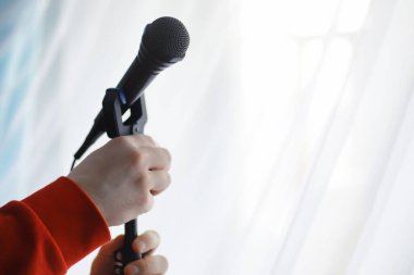 Mikrofonun yanında dur. Adam tripodun üzerinde bir mikrofon tutuyor. Sanatçının bir mikrofonla performansı. Mikrofonlu bir sahne.