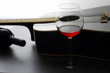 Gitar ve taş arka plan üzerinde kırmızı şarap ile yüksek cam. Masa müzisyeni, kulaklık, mikrofon ve daha fazlası.