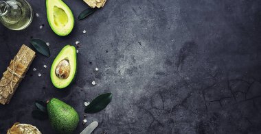Avokado yemek tarifleri. Tahta kesme tahtasında servis edilen olgun yeşil avokado..