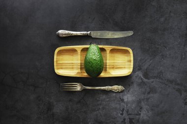 Avokado yemek tarifleri. Tahta kesme tahtasında servis edilen olgun yeşil avokado..