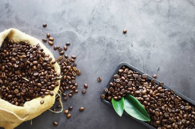Bir poşet kahve. Kahve çekirdekleri masada kavrulmuş. Pişirmek için yapraklı kahve çekirdekleri.