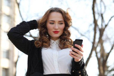 Dışarıda takım elbiseli, cep telefonlu bir iş kadını.