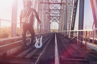 Bir elektro gitar demiryolu üzerinde olan bir adam. Organize sanayi bölgesinde sokakta bir gitar ile deri ceketli bir müzisyen. Köprüde gitarist