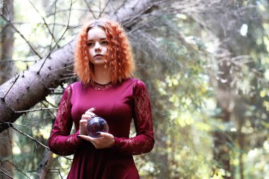 Kızıl saçlı cadı bir ritüel tutan bir kristal topu ile fores