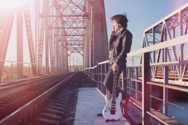 Bir elektro gitar demiryolu üzerinde olan bir adam. Organize sanayi bölgesinde sokakta bir gitar ile deri ceketli bir müzisyen. Köprüde gitarist