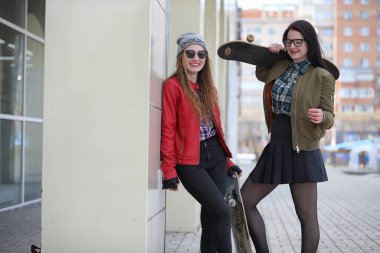 Genç hippi kız bir kaykay sürme. Kızlar kız şehirde bir kaykay ile yürüyüşe. Bahar spor bir kaykay ile sokakta