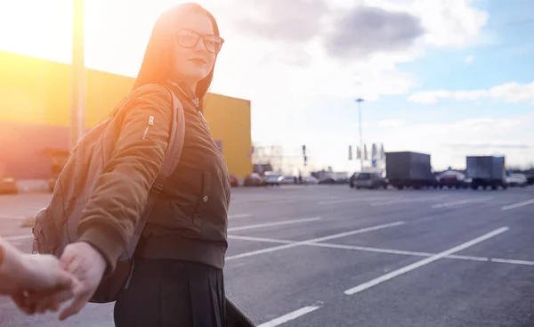 A young hipster girl is riding a skateboard. Girls girlfriends for a walk in city with a skateboard. Spring sports on the street with a skateboard