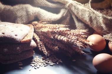 Siyah bir masada buğday ve glüten ile taze somun ekmek. Fırın ve market konsepti. Taze, sağlıklı çavdar ve beyaz somun ekmeği, çuval bezi üzerine serpiştirilmiş un. Tahıllı taze ev yapımı ekmek..