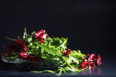 Taze roka kevgirle yapılır. Siyah arka plan. Yeşil yapraklı ve sebzeli yeşil vejetaryen salatası.