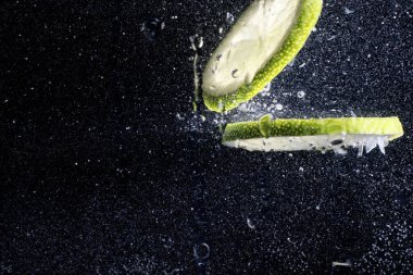 Olgun tatlı limonun üzerine su damlıyor. Metnin için kopyalama alanı olan taze kireç arkaplanı. Vejetaryen ve vejetaryen kavramı.