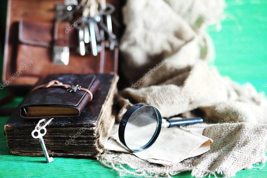 Old leather bag with a magnifying glass on a brown traveler wooden table background copy space.