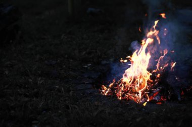Büyük ateşte yanan kızıl kıvılcımlar uçuşur. Yanan kömürler, yanan parçacıklar siyah arkaplanda uçuşuyor..