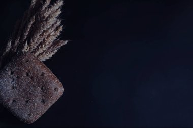 Siyah bir masada buğday ve glüten ile taze somun ekmek. Fırın ve market konsepti. Taze, sağlıklı çavdar ve beyaz somun ekmeği, çuval bezi üzerine serpiştirilmiş un. Tahıllı taze ev yapımı ekmek..