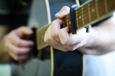 Sahnede telli bir enstrüman çalan sanatçı için akustik gitar. Capo 'lu siyah gitar. Müzik arkaplanı.
