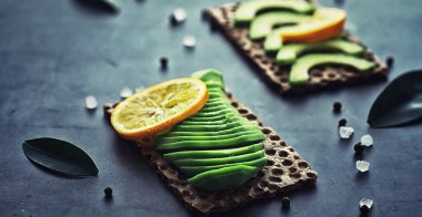 Avokado yemek tarifleri. Tahta kesme tahtasında servis edilen olgun yeşil avokado..