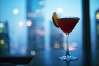Pencere kenarında uzun bir binanın camının yanında kokteyl bardakları.