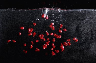 Olgun tatlı nar tohumlarına su damlaları düşer. Metnin için kopyalama alanı olan taze nar arkaplanı. Vejetaryen ve vejetaryen kavramı.