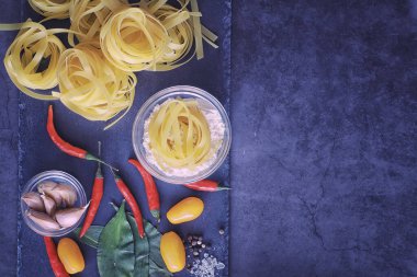 Baharatlı ve sebzeli makarna. Siyah taş üzerinde yemek pişirmek için sebzeli erişte..