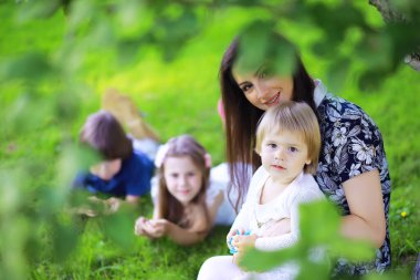 Genç, büyük bir aile yaz sabahı yürüyüşünde. Parkta oynayan çocuklu güzel anne..