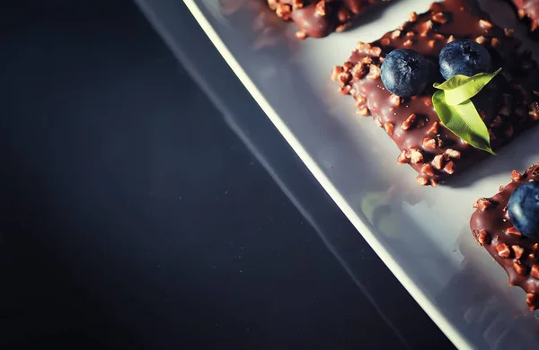 초콜릿 디저트에 견과류와 베리를 곁들인 유약과 과일이 부스러기에 비스킷을 — 스톡 사진