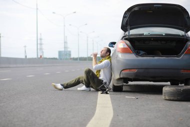 Yoldaki bir arabanın tekerleğini değiştirmek. Kenarda lastik işi yapan bir adam..