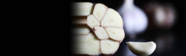 Siyah arka planda taze sarımsaklı karanfil. Sarımsak vitamin açısından zengindir, kullanışlı bahar, iyi baharatlar. Karanlık bir arka planda dilimlenmiş sarımsak. Çiğ sarımsak..