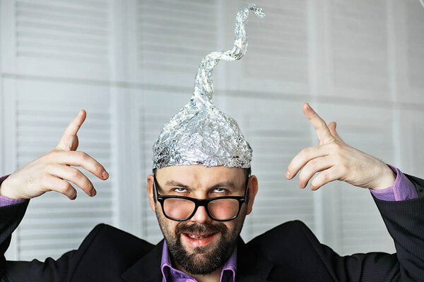 Bearded funny man in cap of aluminum foil. Concept art phobias. Conspiracy theory. Conspiracy. Insanity.