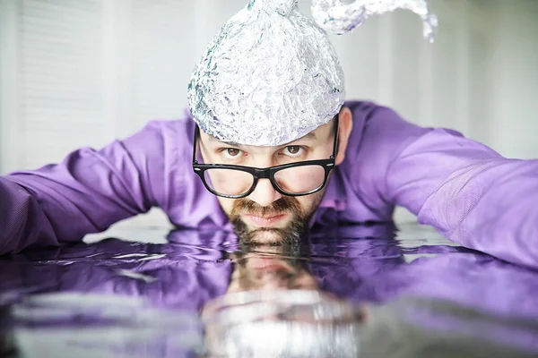 Bearded funny man in cap of aluminum foil. Concept art phobias. Conspiracy theory. Conspiracy. Insanity.