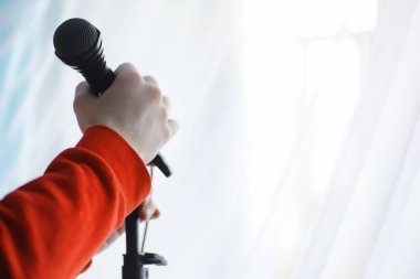 Mikrofonun yanında dur. Adam tripodun üzerinde bir mikrofon tutuyor. Sanatçının bir mikrofonla performansı. Mikrofonlu bir sahne.