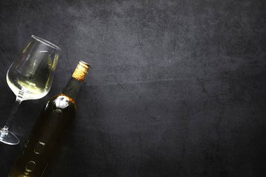 Masada bir bardak kırmızı şarap. Siyah şişe ve bir bardak şarap..