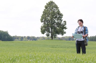 Genç bir adam kaybolmamak için doğadaki haritaya bakar.