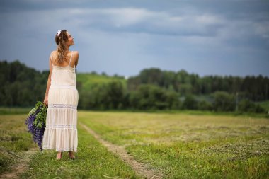 Yazın, elinde bir buket mavi çiçekle güzel bir kız.