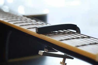 Sahnede telli bir enstrüman çalan sanatçı için akustik gitar. Capo 'lu siyah gitar. Müzik arkaplanı.