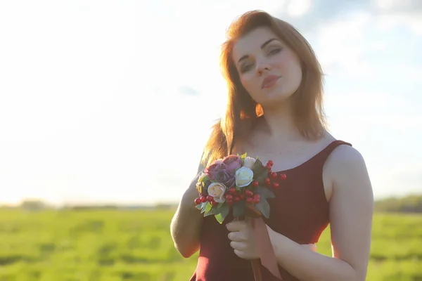 A girl in a hat on a walk in the park. A girl with a basket walks in the spring. Girl is walking along the road at sunset