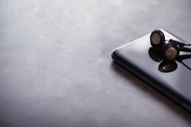 Cep telefonu ve kulaklıklar masada. Başlarken müzik dinle. Çevrimiçi oyuncu. Akıllı telefonlar için ses uygulamaları.