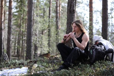 Doğada bir araçla bir müzisyen. Adam bir çam ormanı içinde bir flüt çalıyor. Bahar ormanda Druids müzik