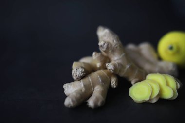 Zencefil kökü bütün ve dilimlenmiş. Koyu arkaplanda limonlu zencefil çayı. Taş zeminde taze zencefil kökü. Vitaminler. Üst Manzara. Metnin için boş yer.