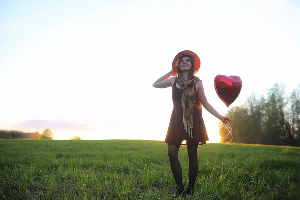 A girl in a hat on a walk in the park. A girl with a basket walks in the spring. Girl is walking along the road at sunset