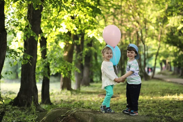 Little children are walking in a park with balloons