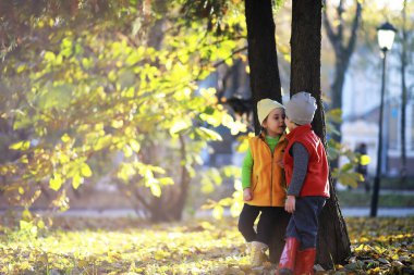 Çocuklar sonbahar parkında sonbaharda yürürler