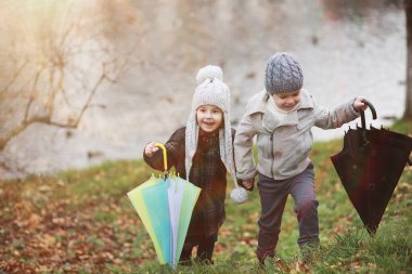 Çocuklar sonbahar parkında sonbaharda yürürler