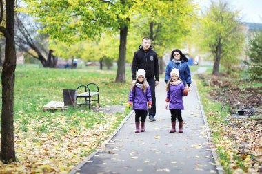 Sonbahar parkında yürüyüşe çıkmış çocuklar. Yaprak parkta düşer. - Aile. Düş! Mutluluk.