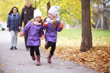 Genç bir aile güneşli bir günde sonbahar parkında yürüyüş yapıyor. Birlikte olmanın mutluluğu..