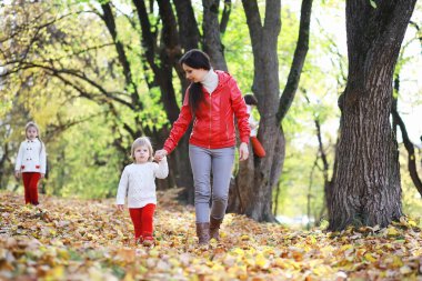 Sonbahar parkında yürüyüşe çıkmış çocuklar. Yaprak parkta düşer. - Aile. Düş! Mutluluk.