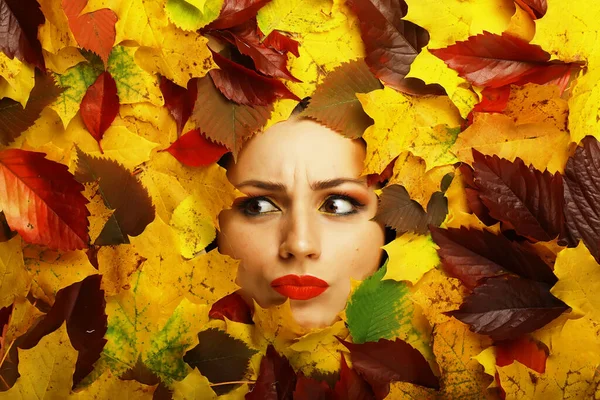 Artistic conceptual autumn portrait. Colorful leaves. Leaves of trees around emotional face. Autumn is coming.