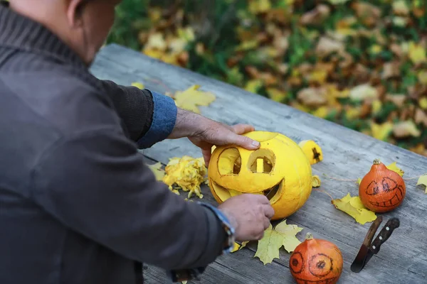 Autumn traditions and preparations for the holiday Halloween. A house in nature, a lamp made of pumpkins is cut out at the table.