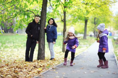 Sonbahar parkında yürüyüşe çıkmış çocuklar. Yaprak parkta düşer. - Aile. Düş! Mutluluk.