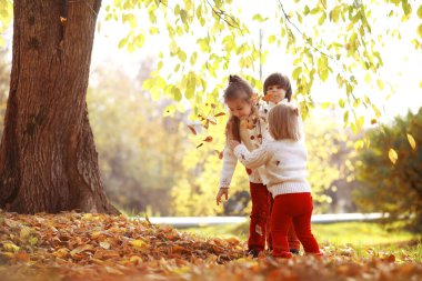 Genç bir aile güneşli bir günde sonbahar parkında yürüyüş yapıyor. Birlikte olmanın mutluluğu..