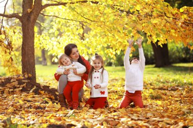 Genç bir aile güneşli bir günde sonbahar parkında yürüyüş yapıyor. Birlikte olmanın mutluluğu..