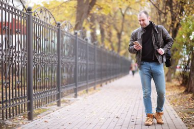 Sonbahar konsepti. Bir adam şehirde yürüyor. Yaya yolunda sonbahar yaprakları